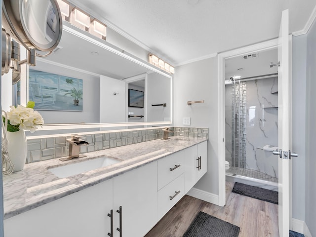 bathroom featuring vanity, backsplash, walk in shower, crown molding, and toilet