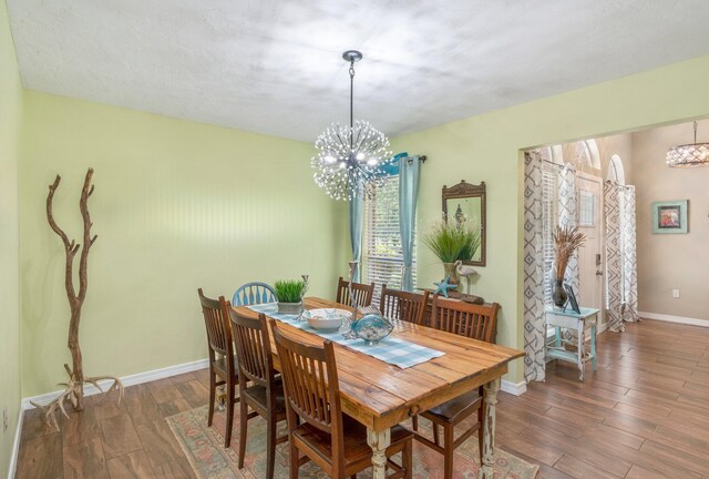 dining area with dark hardwood / wood-style floors and an inviting chandelier