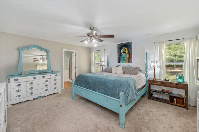 carpeted bedroom featuring multiple windows, ceiling fan, and ensuite bathroom