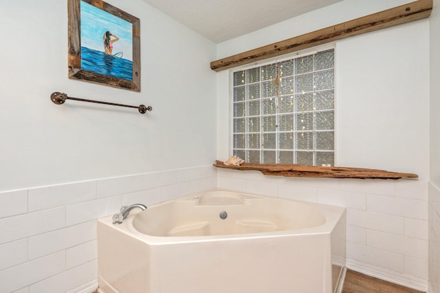 bathroom featuring a textured ceiling, a bathing tub, hardwood / wood-style floors, and tile walls