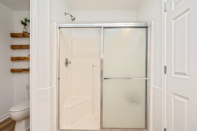 bathroom with a shower with door, wood-type flooring, and toilet