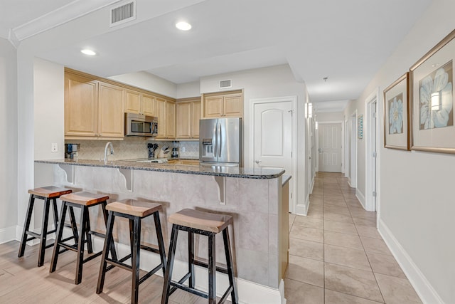 1150 Santa Rosa Blvd Unit 110, Fort Walton Beach, FL 32548 - kitchen featuring kitchen peninsula, stone counters, light brown cabinetry, and stainless steel appliances