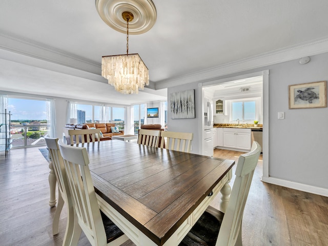 dining room featuring light hardwood / wood-style flooring, ornamental molding, an inviting chandelier, and sink