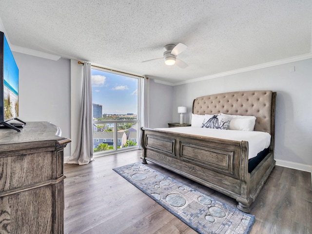 bedroom with a textured ceiling, ornamental molding, dark hardwood / wood-style floors, and ceiling fan