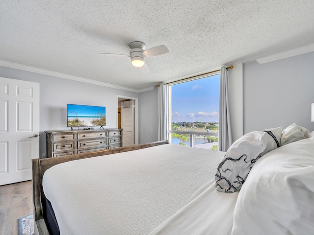 bedroom with a textured ceiling, wood-type flooring, crown molding, and ceiling fan