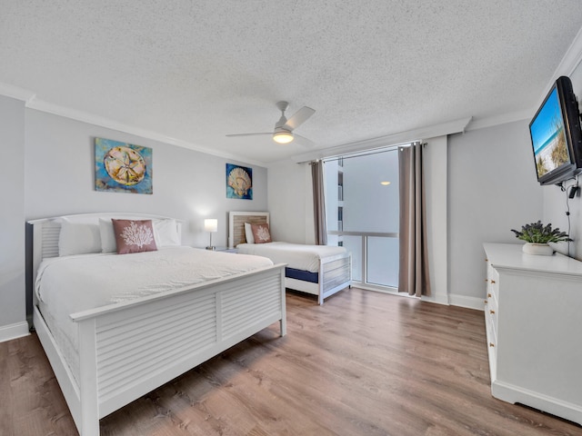 bedroom with a textured ceiling, ornamental molding, ceiling fan, and hardwood / wood-style flooring