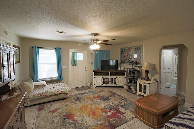 living room with ceiling fan, light tile patterned flooring, and a textured ceiling