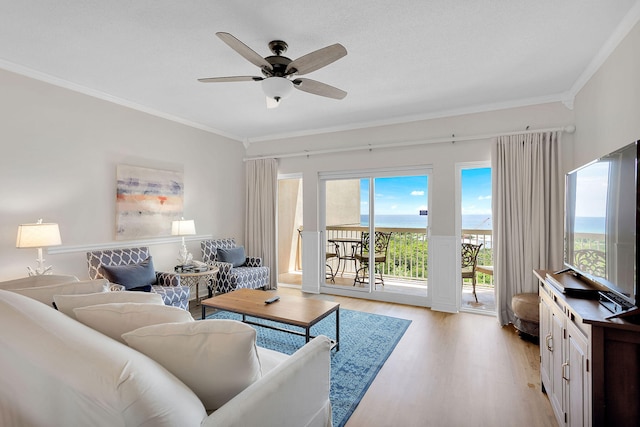 living room featuring light wood-type flooring, ornamental molding, ceiling fan, and a wealth of natural light