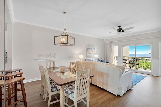 dining space with hardwood / wood-style flooring, ceiling fan with notable chandelier, ornamental molding, and a textured ceiling