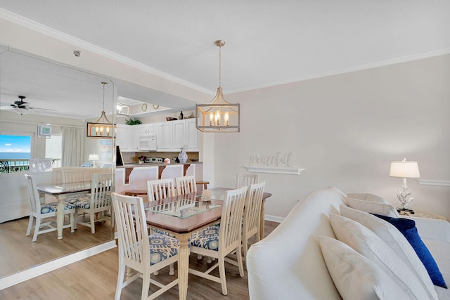 dining room featuring ceiling fan with notable chandelier, light hardwood / wood-style floors, and ornamental molding