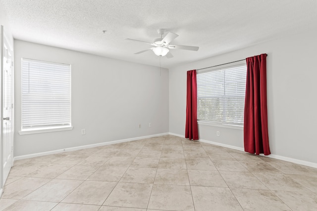 tiled empty room featuring ceiling fan and a textured ceiling