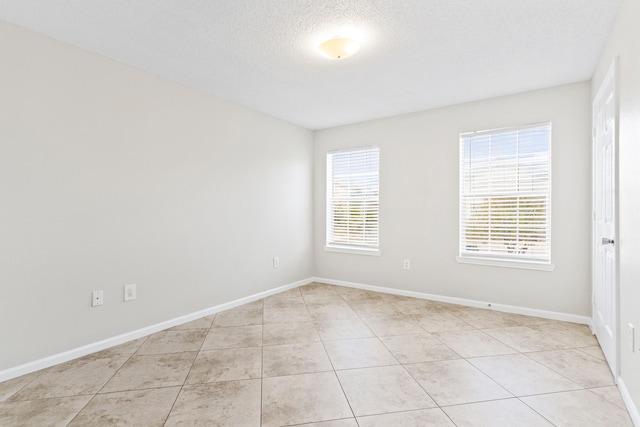 tiled spare room featuring a textured ceiling and a healthy amount of sunlight