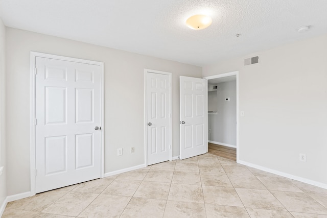 unfurnished bedroom featuring a textured ceiling and light tile patterned floors