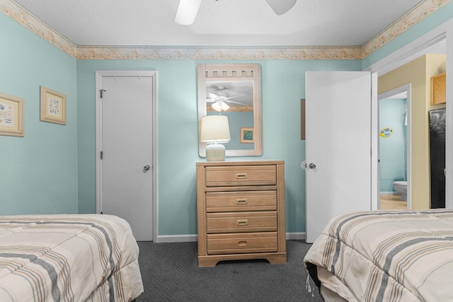 bedroom featuring ceiling fan, a textured ceiling, ensuite bathroom, and dark carpet