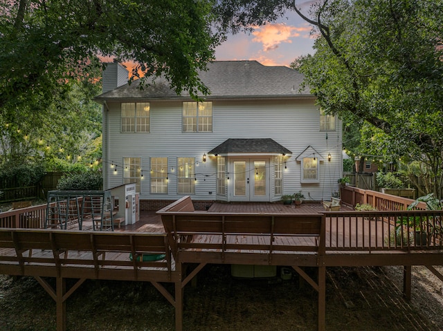 back house at dusk featuring a deck and french doors