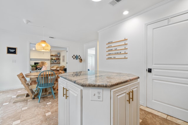 kitchen featuring pendant lighting, light stone counters, white cabinets, a kitchen island, and ornamental molding