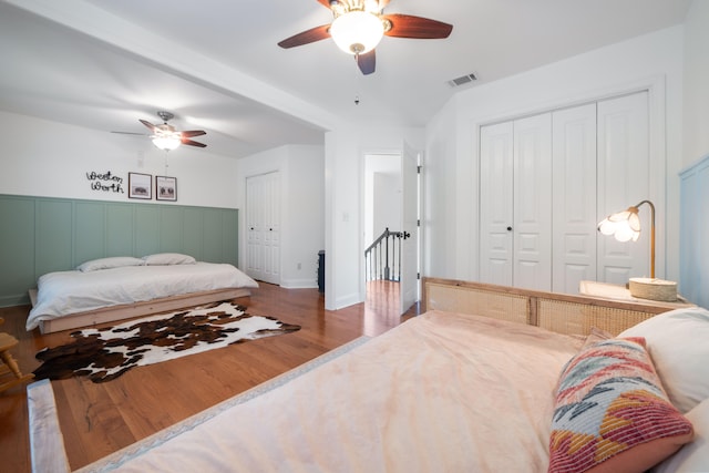 bedroom featuring ceiling fan, two closets, and wood-type flooring