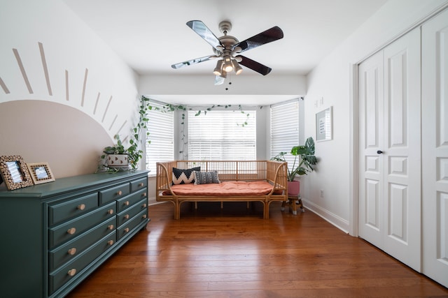 sitting room with ceiling fan and dark wood-type flooring