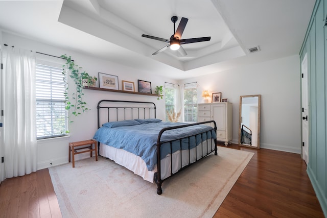 bedroom with ceiling fan, a raised ceiling, and dark hardwood / wood-style floors