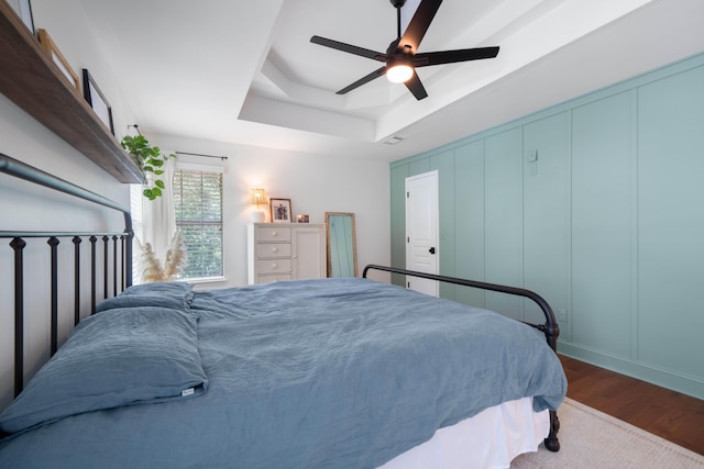 bedroom with a tray ceiling, ceiling fan, and hardwood / wood-style flooring