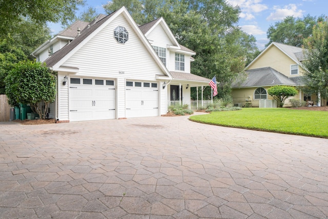 view of property with a garage, covered porch, and a front yard