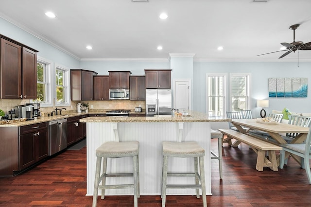 kitchen with dark hardwood / wood-style floors, a kitchen island, light stone counters, and appliances with stainless steel finishes