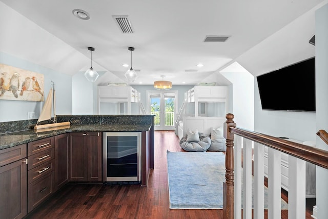 kitchen with hanging light fixtures, beverage cooler, dark hardwood / wood-style floors, dark stone countertops, and vaulted ceiling