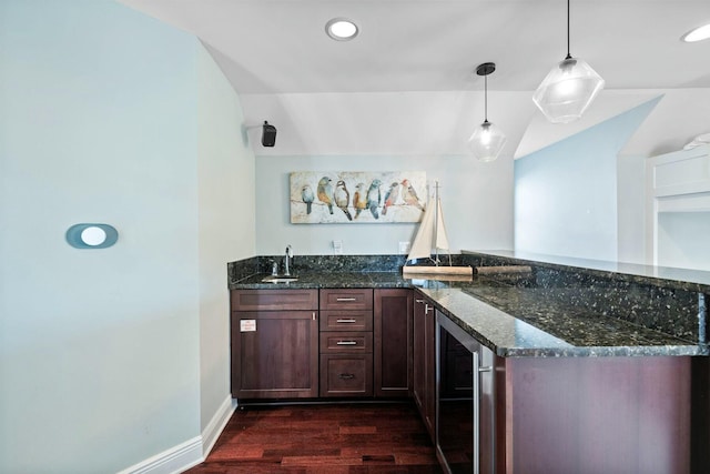 bar featuring sink, hanging light fixtures, dark stone countertops, dark hardwood / wood-style flooring, and beverage cooler