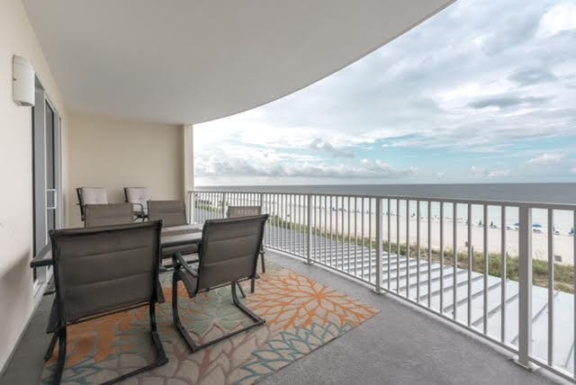 balcony featuring a water view and a beach view