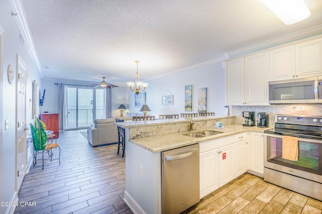 kitchen featuring a peninsula, appliances with stainless steel finishes, wood finish floors, and a sink