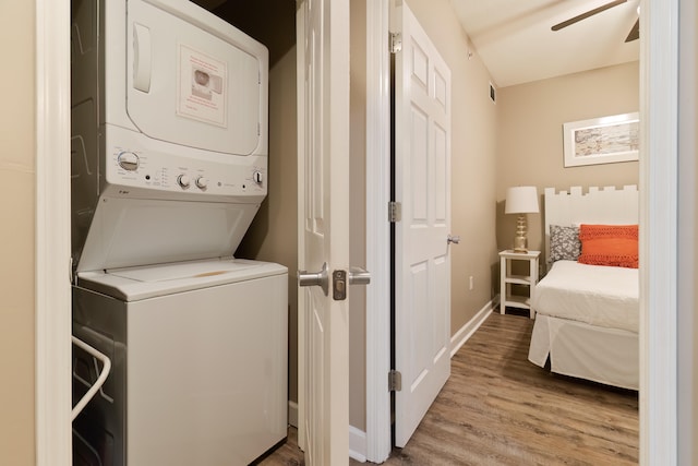 washroom featuring ceiling fan, hardwood / wood-style flooring, and stacked washing maching and dryer