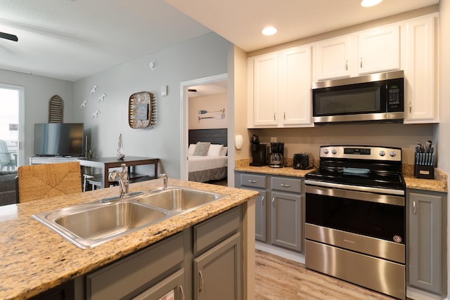 kitchen featuring gray cabinets, stainless steel appliances, white cabinetry, and sink