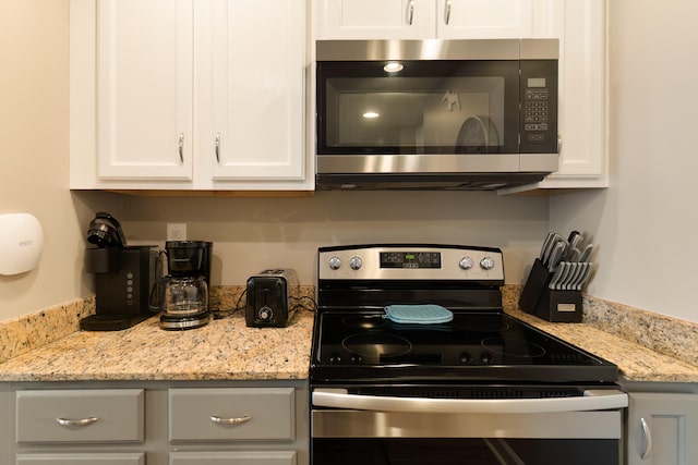 kitchen with light stone countertops, white cabinets, and appliances with stainless steel finishes