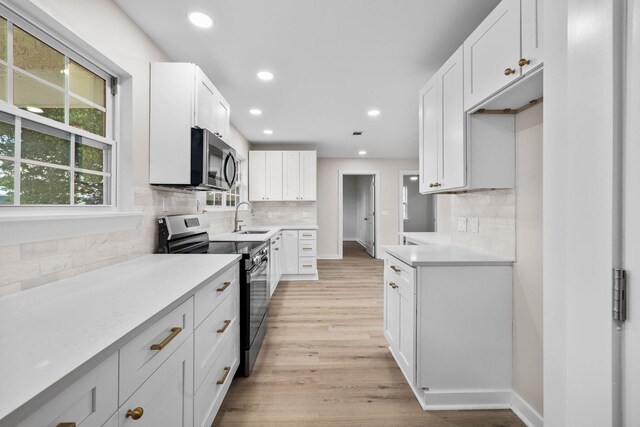 kitchen featuring white cabinets, backsplash, stainless steel appliances, light hardwood / wood-style flooring, and sink