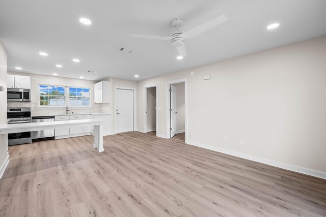 kitchen with stainless steel appliances, white cabinets, ceiling fan, and light hardwood / wood-style floors