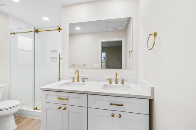 bathroom with hardwood / wood-style floors, vanity, toilet, and a shower with shower door