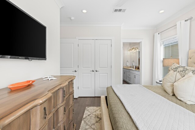 bedroom featuring a closet, dark hardwood / wood-style floors, ensuite bathroom, and crown molding