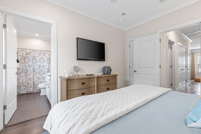 bedroom featuring dark hardwood / wood-style floors, ornamental molding, and ensuite bath