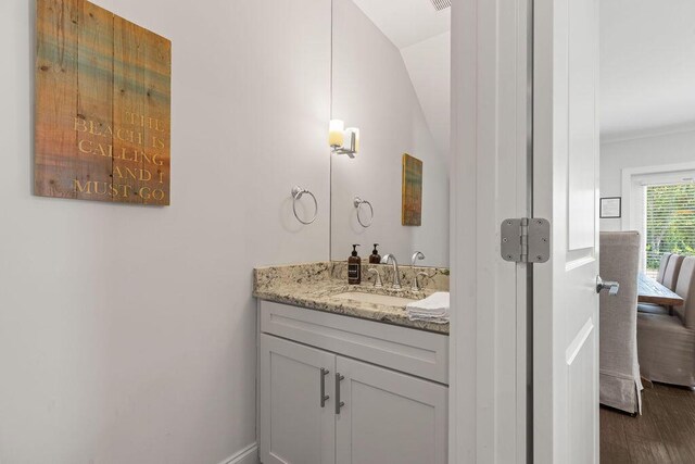 bathroom with wood-type flooring, lofted ceiling, and vanity