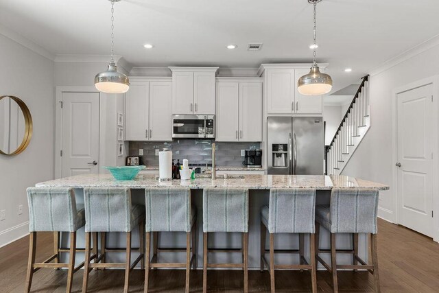 kitchen with appliances with stainless steel finishes, a center island with sink, and white cabinets