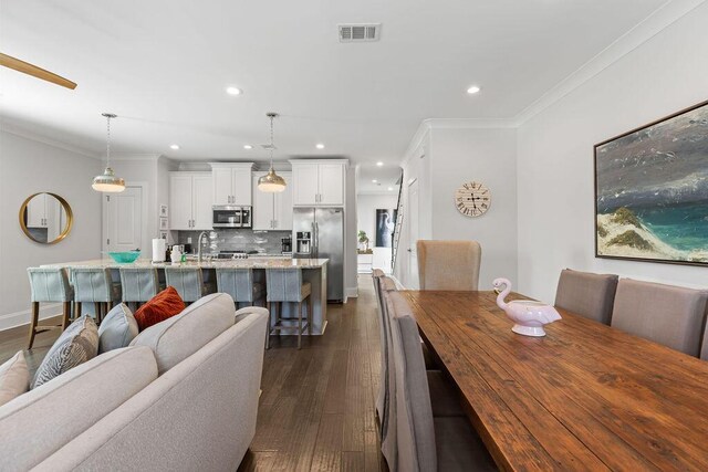 dining area featuring ornamental molding, dark hardwood / wood-style floors, and sink