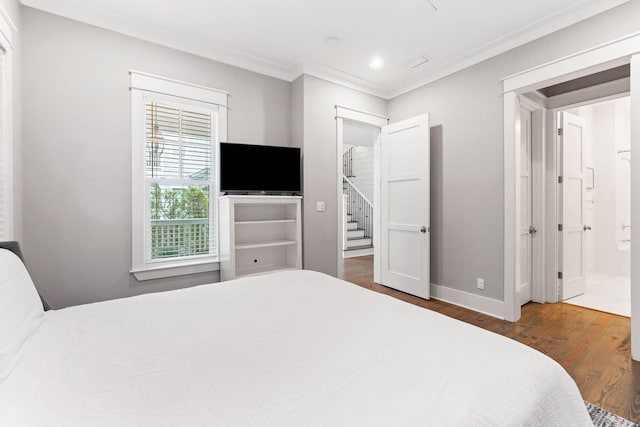 bedroom featuring connected bathroom, dark wood-type flooring, and crown molding