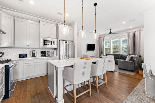 kitchen with a kitchen island with sink, high end appliances, dark hardwood / wood-style floors, and hanging light fixtures