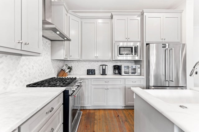 kitchen featuring wall chimney range hood, high end appliances, and white cabinets