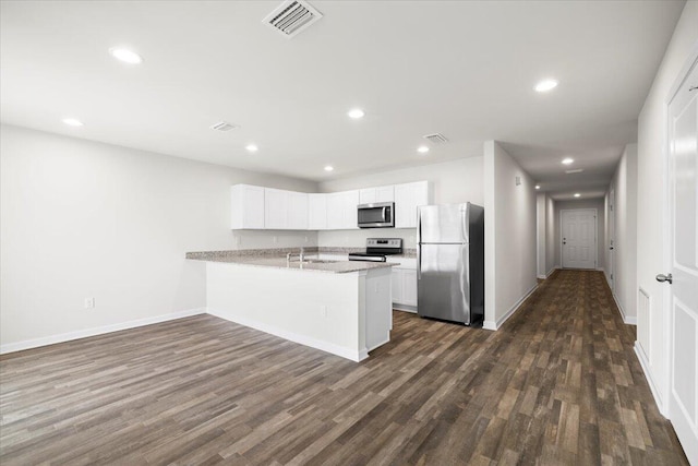 kitchen with stainless steel appliances, dark wood-type flooring, kitchen peninsula, and white cabinetry