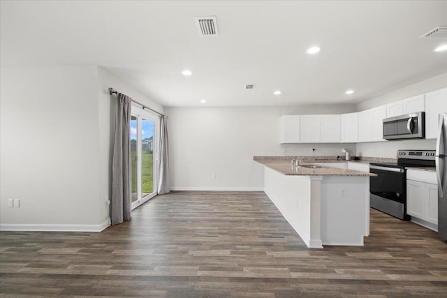 kitchen with appliances with stainless steel finishes, white cabinetry, dark hardwood / wood-style flooring, and light stone counters