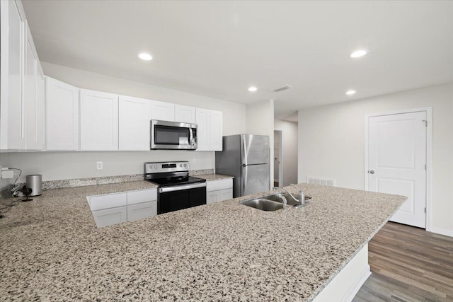 kitchen with appliances with stainless steel finishes, white cabinetry, kitchen peninsula, dark hardwood / wood-style floors, and sink