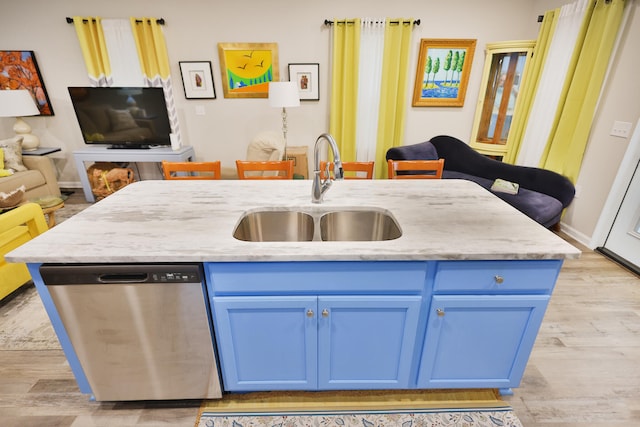 kitchen with stainless steel dishwasher, a kitchen island with sink, sink, and blue cabinets