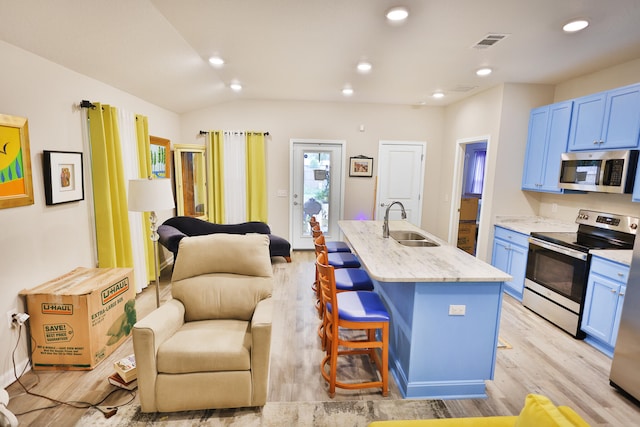 kitchen with a breakfast bar, stainless steel appliances, lofted ceiling, a center island with sink, and sink