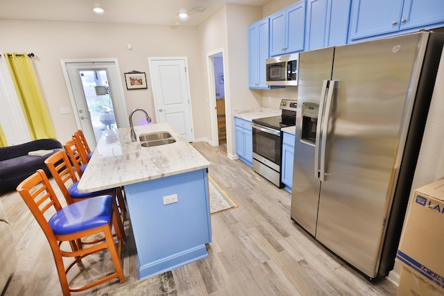 kitchen featuring a breakfast bar, light wood-type flooring, sink, a center island with sink, and appliances with stainless steel finishes